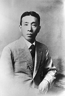 Shinjiro Torii in a suit, photographed in a formal studio portrait.